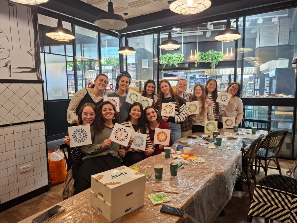 תלמידות מציגות אריחי קרמיקה שציירו בסדנת עיצוב
